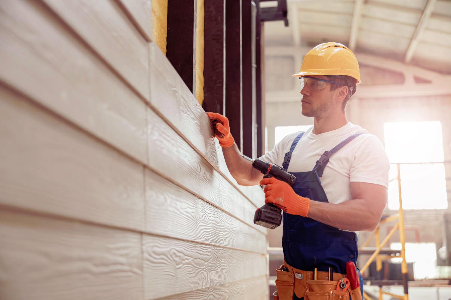 young man builder installing exterior wood siding