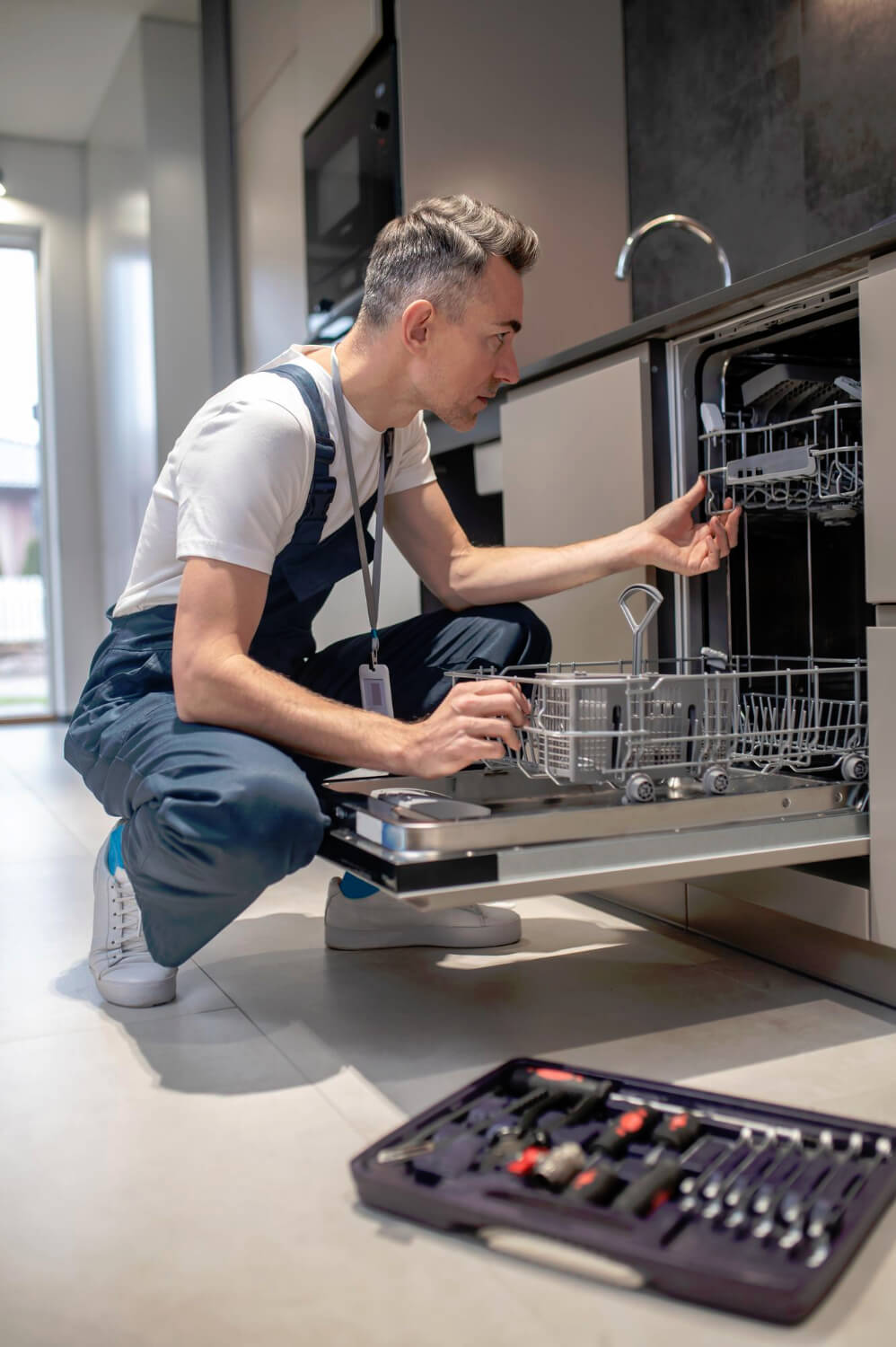 Diagnostics of equipment profile of serious man looking at open dishwasher in kitchen