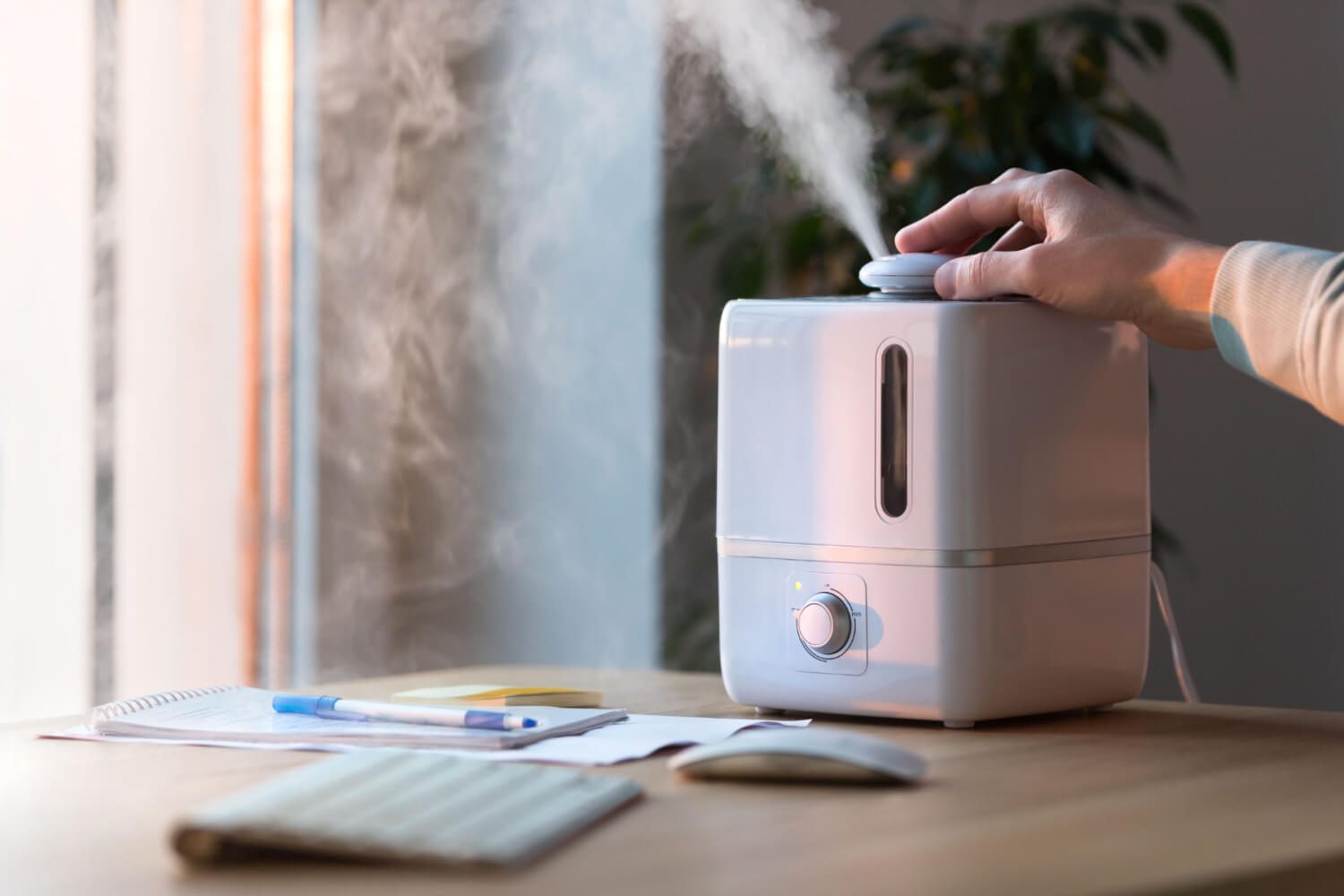 Man using aroma oil diffuser on the table, steam from the air humidifier, selective focus
