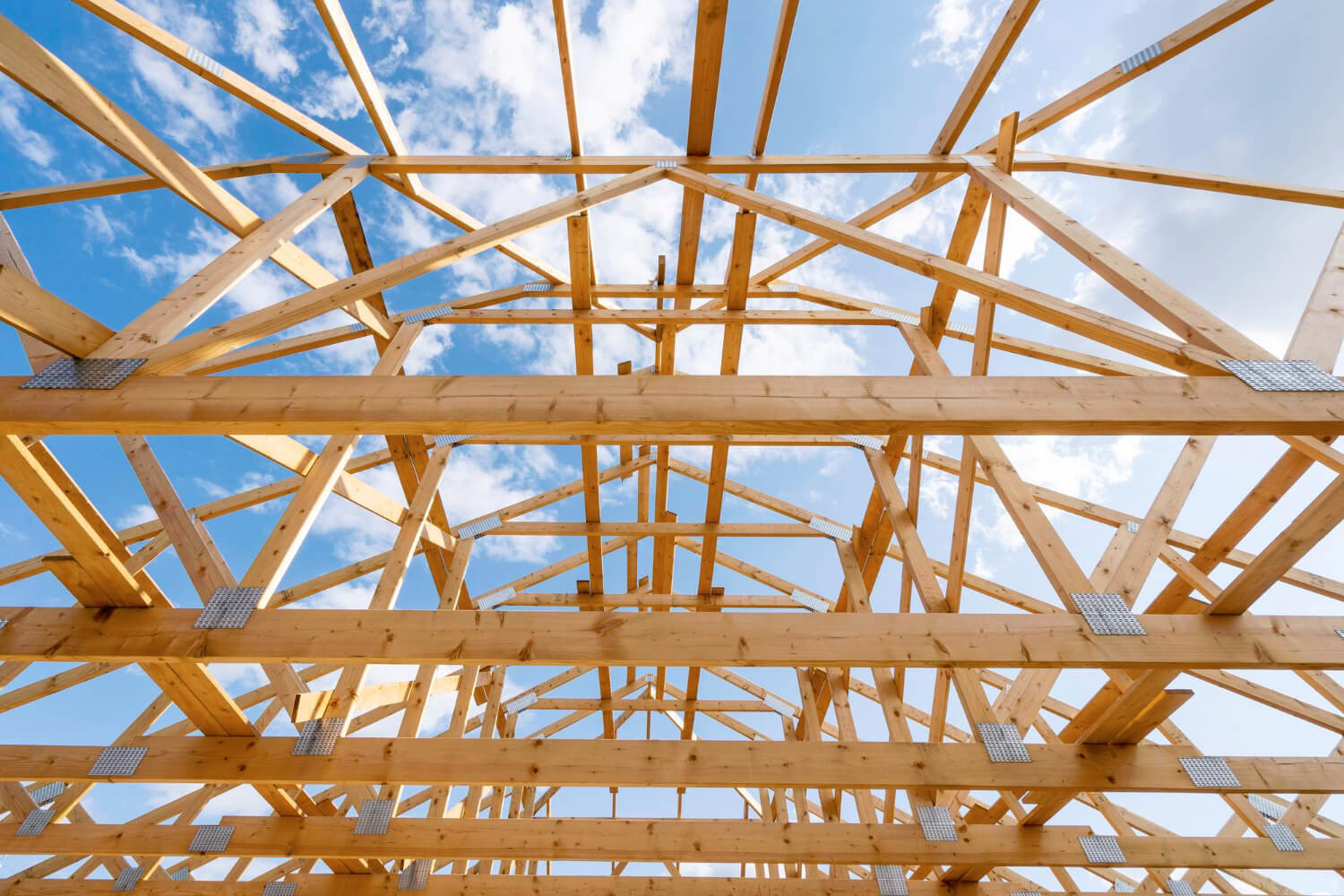 Unfinished attic space with wooden framework construction against blue sky background