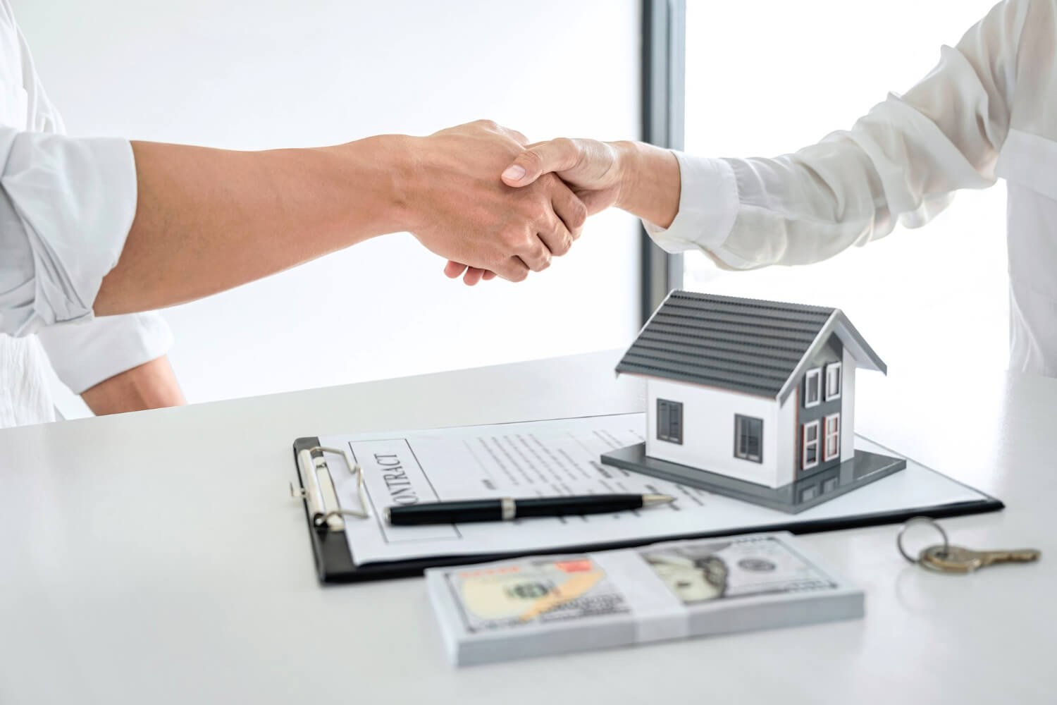 Real estate agent and customers shaking hands together celebrating finished contract after signing about home insurance and investment loan, handshake and successful deal.